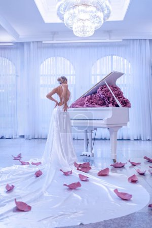 Téléchargez les photos : Belle femme avec piano blanc et pivoines fleurs en studio blanc - en image libre de droit