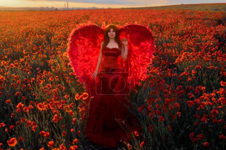 Photo for Beautiful woman with red wings in poppies field - Royalty Free Image