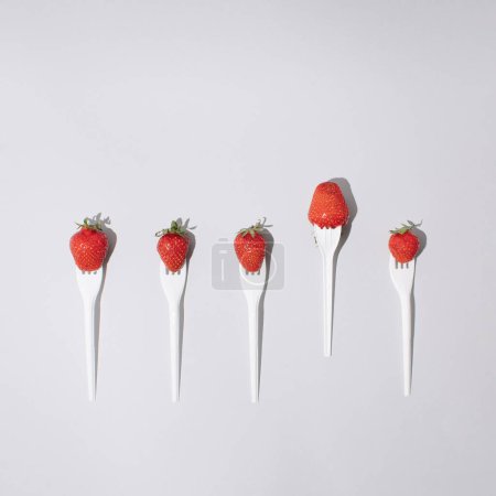 Foto de Repetir collage de tenedor con fresa sobre fondo brillante. Concepto de alimentos de frutas dulces. - Imagen libre de derechos
