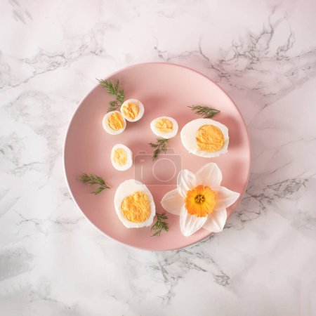 Boiled chicken and quail eggs and narcissus on pink plate on kitchen marble background. Healthy raw food concept