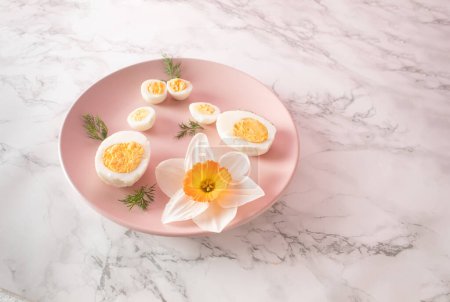 Boiled chicken and quail eggs and narcissus on pink plate on kitchen marble background. Healthy raw food concept