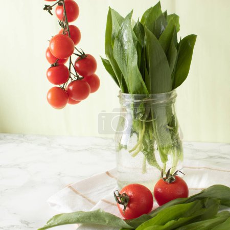 Ramsons et tomates cerises sur une surface de travail en marbre dans une cuisine. Concept d'alimentation saine