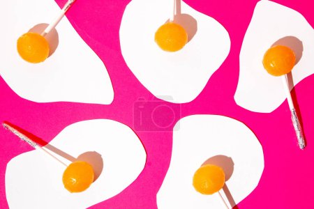 Photo for Egg made of white papers and orange lollipops against hot pink background. Flat lay. Creative pattern - Royalty Free Image
