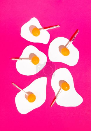 Foto de Huevo hecho de libros blancos y piruletas de color naranja sobre fondo rosa intenso. Acostado. Patrón creativo - Imagen libre de derechos