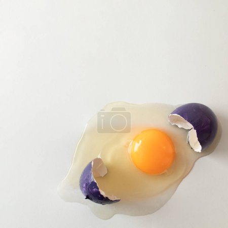 Photo for Cracked purple eggshell with raw egg. Creative copy space on light background. Minimal Easter concept. - Royalty Free Image