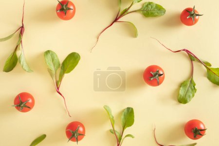 Creative arranged deconstructed salad of cherry tomatoes and baby beets arranged on a pastel yellow background