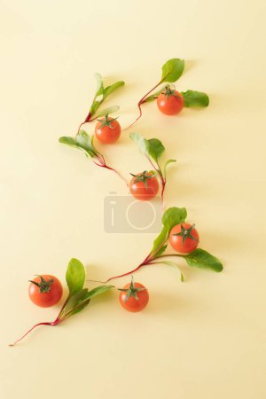 Creative pattern of cherry tomatoes and baby beets arranged on a pastel yellow background