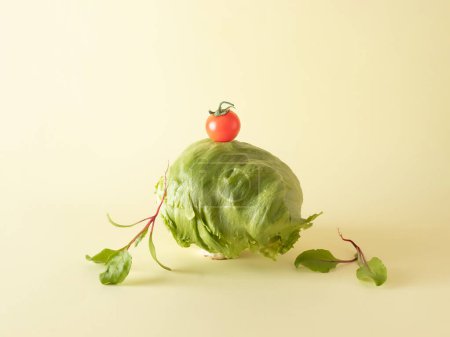 Extraño y divertido bodegón de verduras lechuga iceberg, tomate cereza y hojas de remolacha bebé apilados uno encima del otro