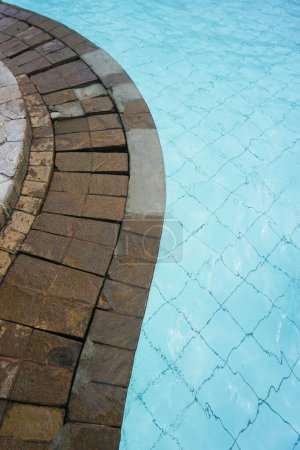 Foto de Piscina curva bord, agua y textura de piedra natural. espacio de copia - Imagen libre de derechos