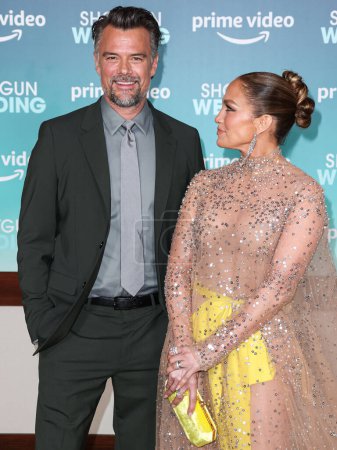 Photo for Josh Duhamel and  Jennifer Lopez (J.Lo) wearing a Valentino sheer dress and Tyler Ellis clutch arrive at the Los Angeles Premiere Of Amazon Prime Video's 'Shotgun Wedding' on January 18, 2023 in Hollywood, Los Angeles - Royalty Free Image