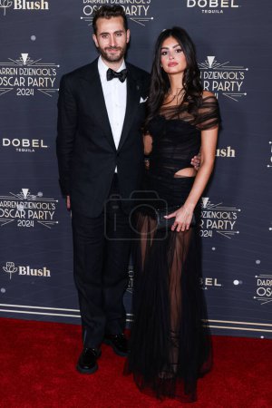 Téléchargez les photos : Darren Dzienciol et Jacqueline Bazbaz arrivent à l'Oscar Party 2024 de Darren Dzienciol qui se tient dans une résidence privée le 8 mars 2024 à Bel Air, Los Angeles, Californie, États-Unis. - en image libre de droit
