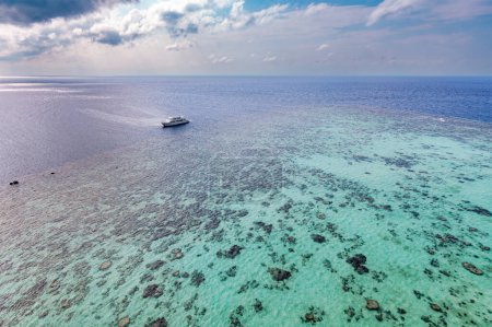 Téléchargez les photos : Un bateau de plongée se repose à côté d'un récif corallien animé dans la mer Rouge soudanaise, comme on le voit depuis le phare de Sanganeb. Beauté tranquille de l'exploration sous-marine. - en image libre de droit