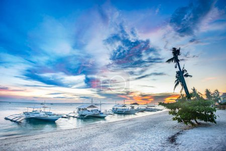 Téléchargez les photos : Vue panoramique de bateaux de plongée amarrés près de la plage au coucher du soleil avec un ciel spectaculaire à Malapascua, Philippines. - en image libre de droit