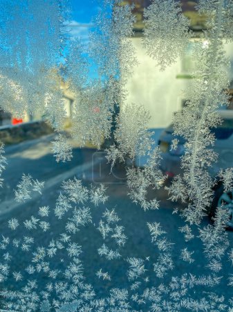 Faszinierende Eiskristalle formen komplizierte Muster auf einem Autofenster und schaffen eine winterliche Wunderwelt. Nahaufnahme von frostigem Glas.