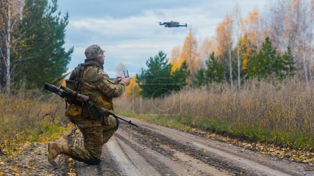 Photo for Photo of a mercenary soldier launch a reconnaissance drone on the road in a forest. Modern technological methods of reconnaissance and warfare. - Royalty Free Image