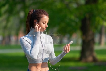 Photo for Photo of a young woman jogging. She seting up the music on her smartphone for a good jogging mood. The concept of keeping yourself in good shape. - Royalty Free Image