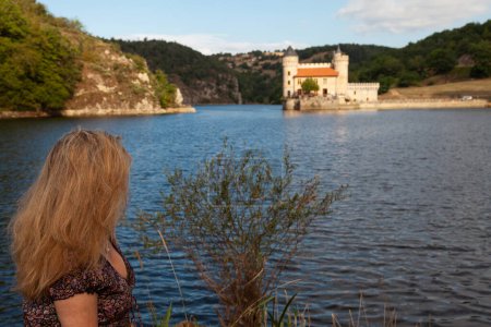 Photo for Beautiful middle aged woman from behind on a small rock in the middle of a french lake - summer holidays concept - Royalty Free Image