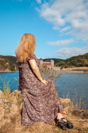 Photo for Beautiful middle aged woman from behind on a small rock in the middle of a french lake - summer holidays concept - Royalty Free Image
