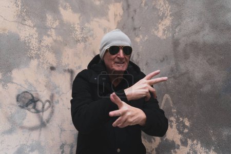 Téléchargez les photos : Homme mûr chanteur de rap posant dans la rue à la périphérie d'une grande ville - en image libre de droit