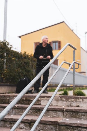 Photo for Mature man rap singer posing on stairs outdoors on the outskirts of a big city - defocused image - Royalty Free Image