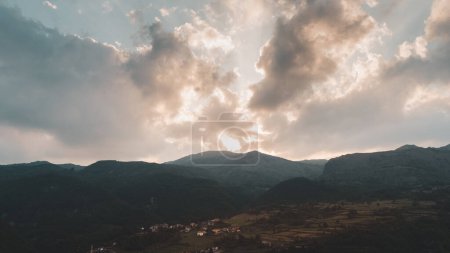 Photo for Panoramic view of a valley surrounded by hills at sunset with the sun obscured by clouds - Royalty Free Image