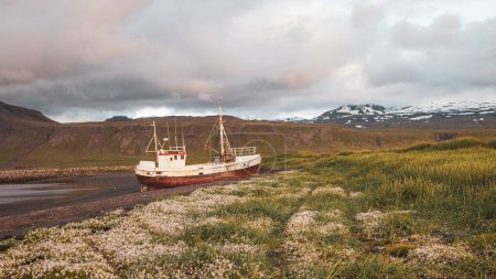 Téléchargez les photos : Abandoned vessel stranded on a beach on the Icelandic coast in the light of the midnight sun - en image libre de droit