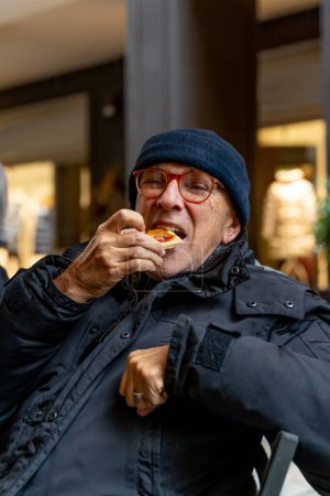 Foto de Elegant mature man having a snack sitting in an outdoor cafe in winter - Imagen libre de derechos