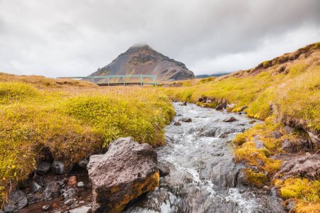 Téléchargez les photos : Landscape of typical icelandic nature river and grass in summer - volcano and cloudy sky in the background - en image libre de droit