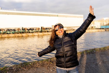 Téléchargez les photos : Femme d'âge moyen portant des vêtements d'hiver en s'amusant près d'une rivière - les gens dans le concept de loisirs - en image libre de droit