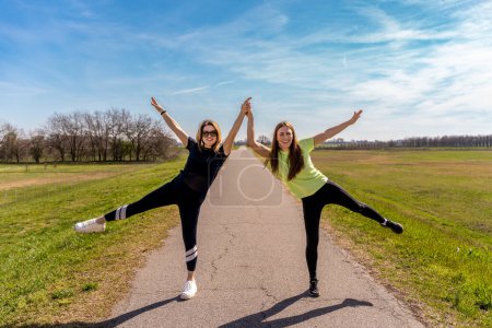 Foto de Pareja de mujeres muy atléticas haciendo ejercicios de gimnasia al aire libre - concepto de bienestar - Imagen libre de derechos