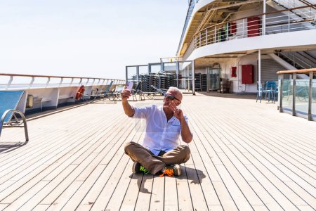 Photo for Happy handsome middle aged man taking a selfie on the deck of a cruise ship - travel and vacation concept - Royalty Free Image