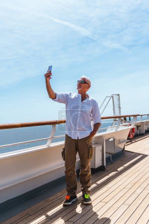 Téléchargez les photos : Heureux homme d'âge moyen beau prenant un selfie sur le pont d'un bateau de croisière - Voyage et vacances concept - en image libre de droit