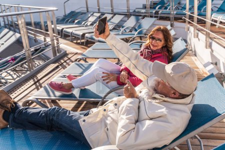 Téléchargez les photos : Beau couple d'âge moyen heureux prenant un selfie avec smartphone sur un bateau de croisière - concept de voyage et de vacances - en image libre de droit