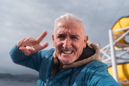 Téléchargez les photos : Bel homme d'âge moyen prenant un selfie sur le pont d'un navire - Heureux touriste voyageant par bateau de croisière - Concept de tourisme et de vacances - en image libre de droit