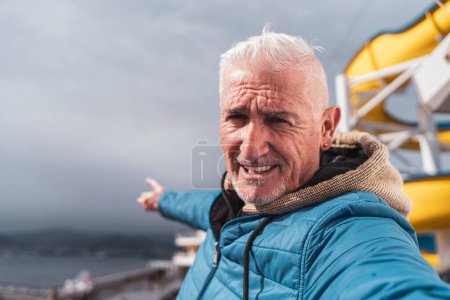 Téléchargez les photos : Bel homme d'âge moyen prenant un selfie sur le pont d'un navire - Heureux touriste voyageant par bateau de croisière - Concept de tourisme et de vacances - en image libre de droit