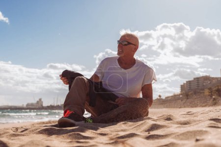 Photo for Handsome middle aged man relaxing sitting on a beach in Tarragona, spain - Tourism and holidays concept - Royalty Free Image