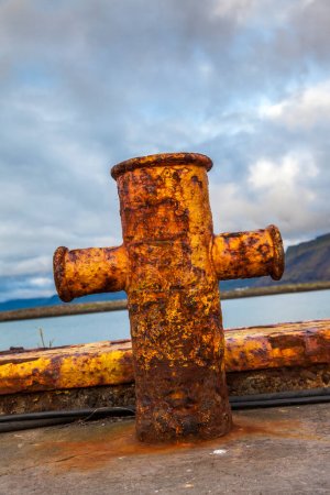 Téléchargez les photos : Borne en fer rouillé pour ancrer les navires sur une jetée islandaise devant un ciel nuageux - en image libre de droit