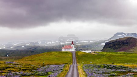 Photo for Isolated white church on a hill in front of snowcapped mountains in iceland - Royalty Free Image