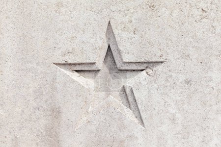 Téléchargez les photos : Détail en forme d'étoile sculpté dans un mur en béton - fond en stuc gris - en image libre de droit