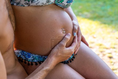 Téléchargez les photos : Gros plan sur le ventre d'une femme enceinte caressée par les mains de son mari - en image libre de droit