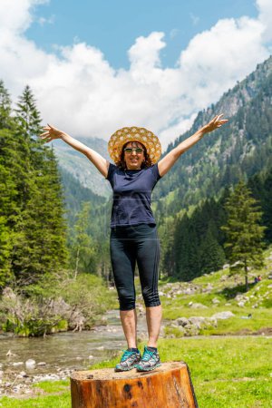 Photo for Beautiful middle-aged woman having fun posing during a walk in the mountains among the pine trees - Royalty Free Image