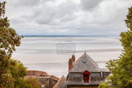 Foto de Vista panorámica de la marea baja desde los tejados de las casas del pueblo fortificado de mont saint michel normandía francia - Imagen libre de derechos