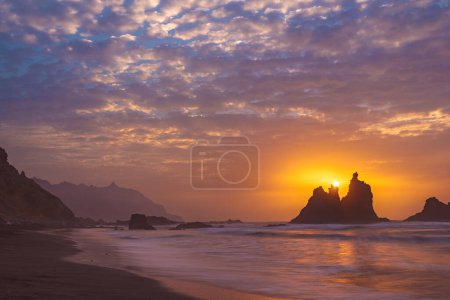 Foto de Ardiente atardecer de verano detrás de las rocas típicas de la playa de Benijio en el noreste de la isla de tenerife - concepto de viaje - Imagen libre de derechos