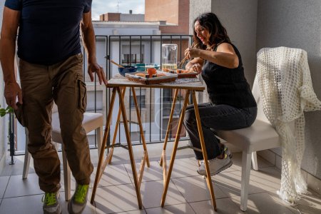 Foto de Hermosa pareja de mediana edad comiendo comida china llevar sentado en una mesa puesta en un balcón de la ciudad - Imagen libre de derechos