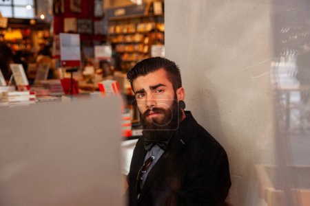 Téléchargez les photos : Jeune homme d'affaires faisant une pause dans un café - vue à travers le magasin jeune homme d'affaires faisant une pause dans un café - vue à travers la vitrine - en image libre de droit