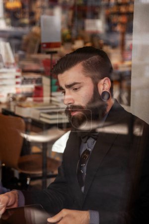 Foto de Joven hombre de negocios tomando un descanso en un café - ver a través de tienda joven hombre de negocios tomando un descanso en un café - ver a través de escaparate - Imagen libre de derechos