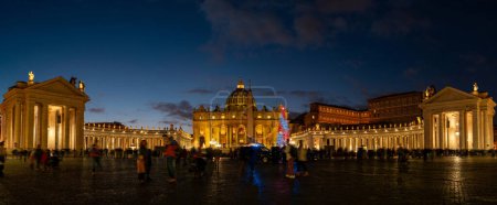 Téléchargez les photos : Vue nocturne de la basilique Saint-Pierre illuminée par le sapin de Noël et bondée de personnes occupées à Rome - en image libre de droit