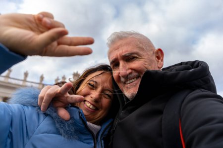 Foto de Feliz pareja de mediana edad de vacaciones tomando un selfie frente a la basílica de San Pedro en Roma - diversión y concepto de vacaciones. - Imagen libre de derechos