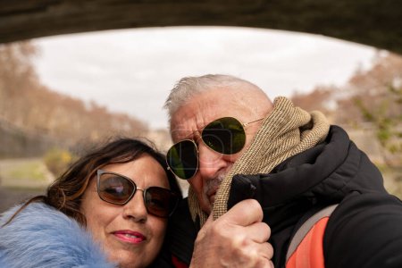 Foto de Feliz pareja de mediana edad de vacaciones tomando una selfie en las orillas del Tíber en Roma - diversión y concepto de vacaciones. - Imagen libre de derechos