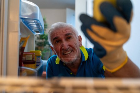 Foto de Hombre soltero de mediana edad limpiando la nevera alegremente - vista desde el interior del electrodoméstico - Imagen libre de derechos